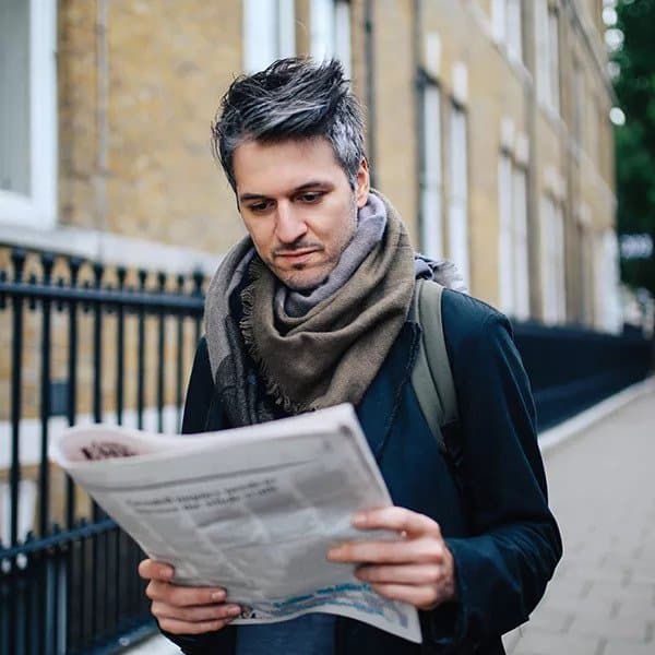 A business owner reading the local newspaper to see the latest print ads in their area