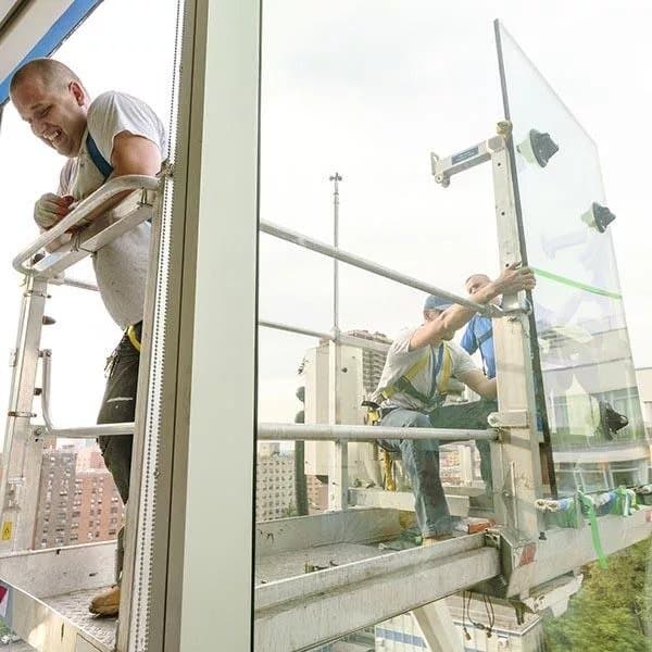 A team of builders fitting glass panels to an office building