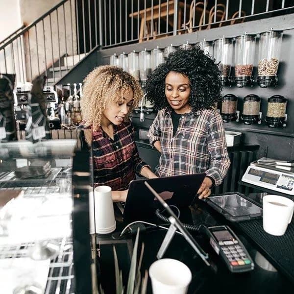 Two baristas in a café searching for a UK-video marketing agency on their tablet