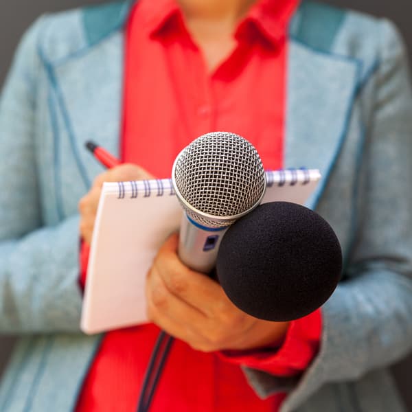 Female journalist holding a notepad and microphone